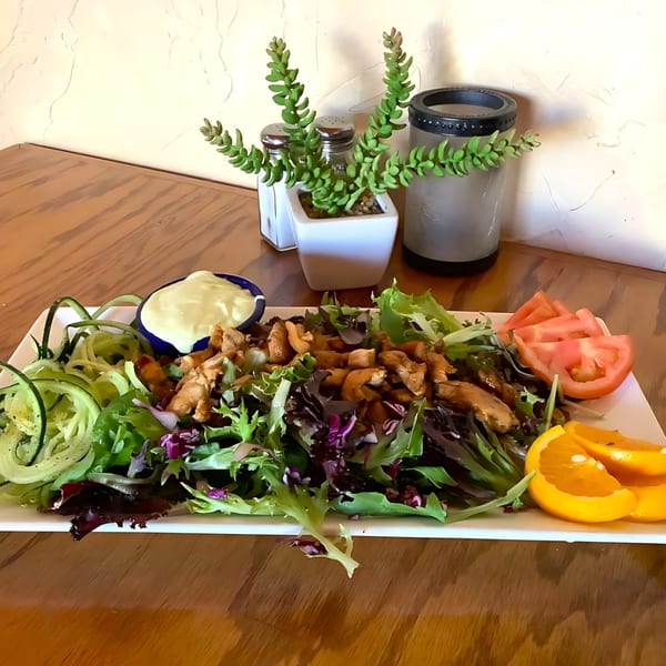 El Jardin's chicken salad with mixed greens, cucumber, tomatoes, oranges, and a side of dressing.