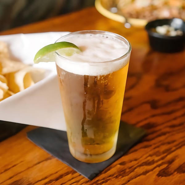 A cold glass of beer with a lime wedge on a wooden table at El Jardin.